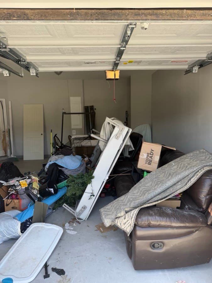 Cluttered garage full of furniture and boxes before an OnCall cleanout